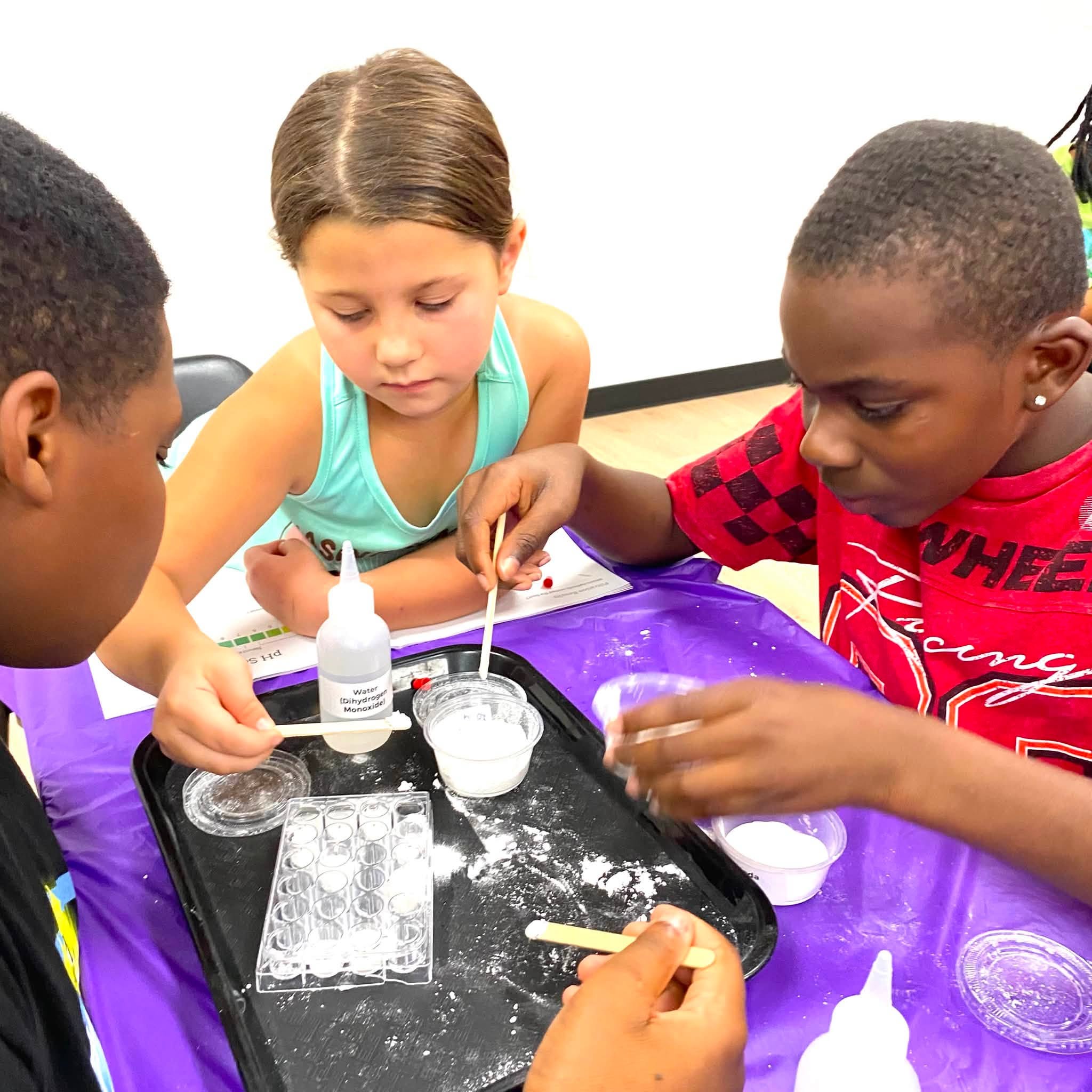 A girl and two boys doing a science experiment using a powder and liquid.